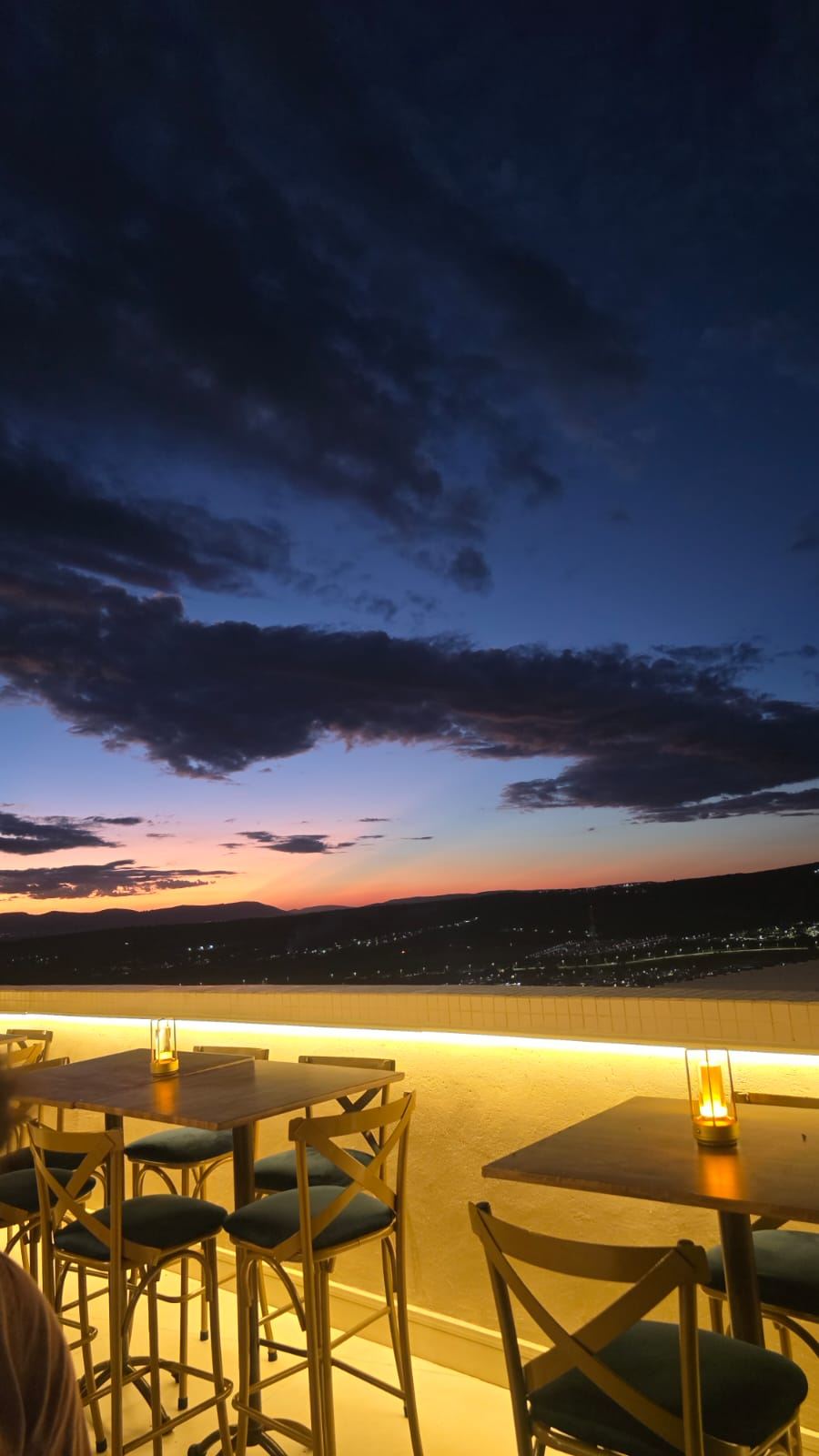 Mesas com luminárias junto ao parapeito ao entardecer