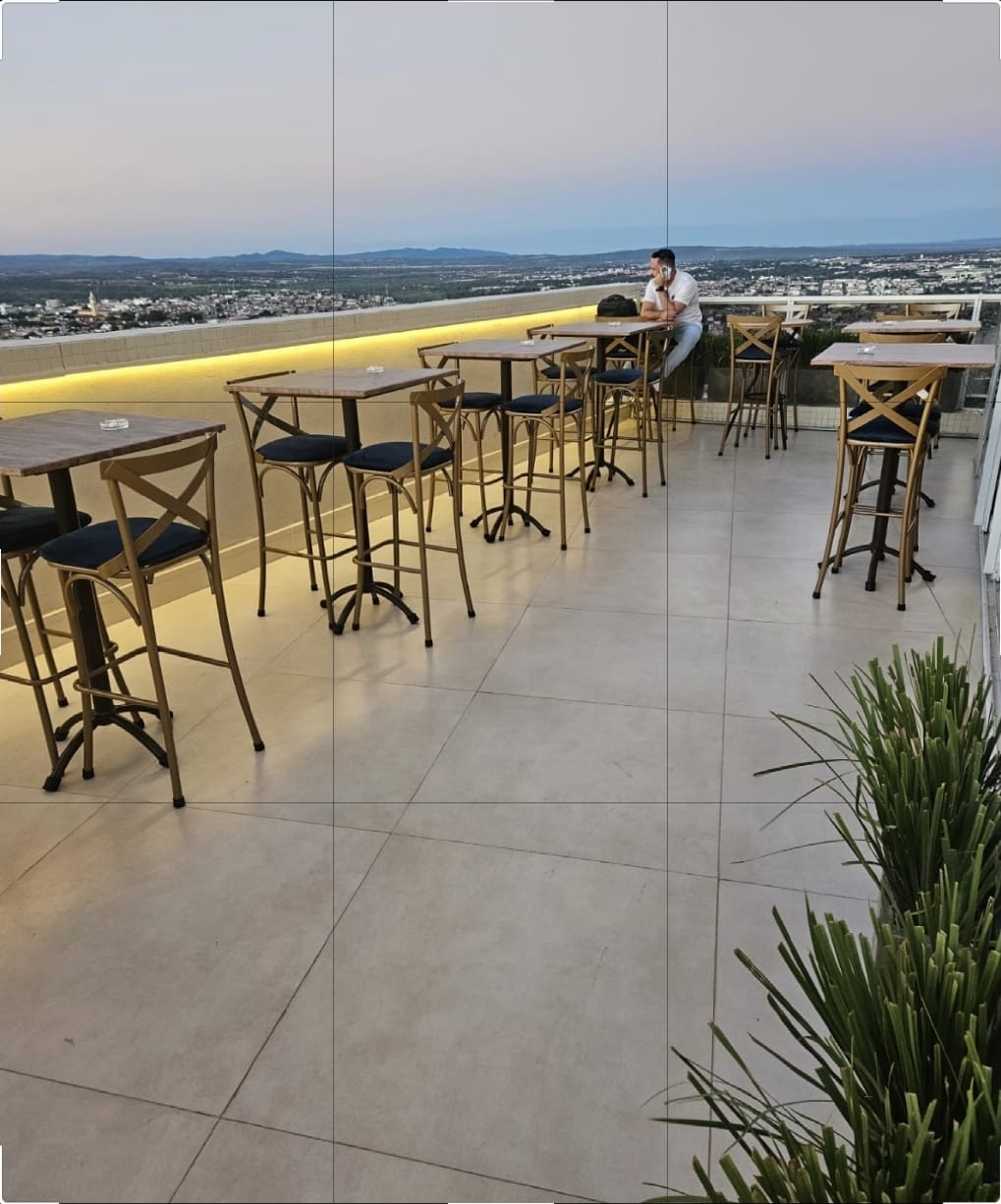 Mesas altas no terraço, de frente para a cidade ao entardecer