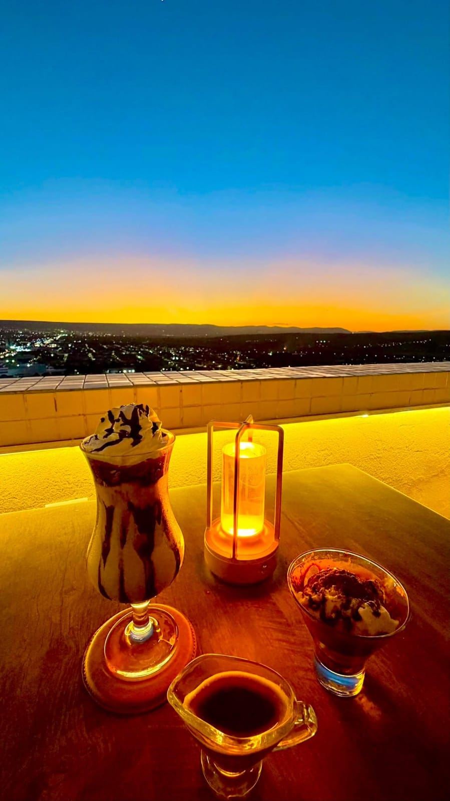 Sobremesas e café à luz de vela com o pôr do sol ao fundo
