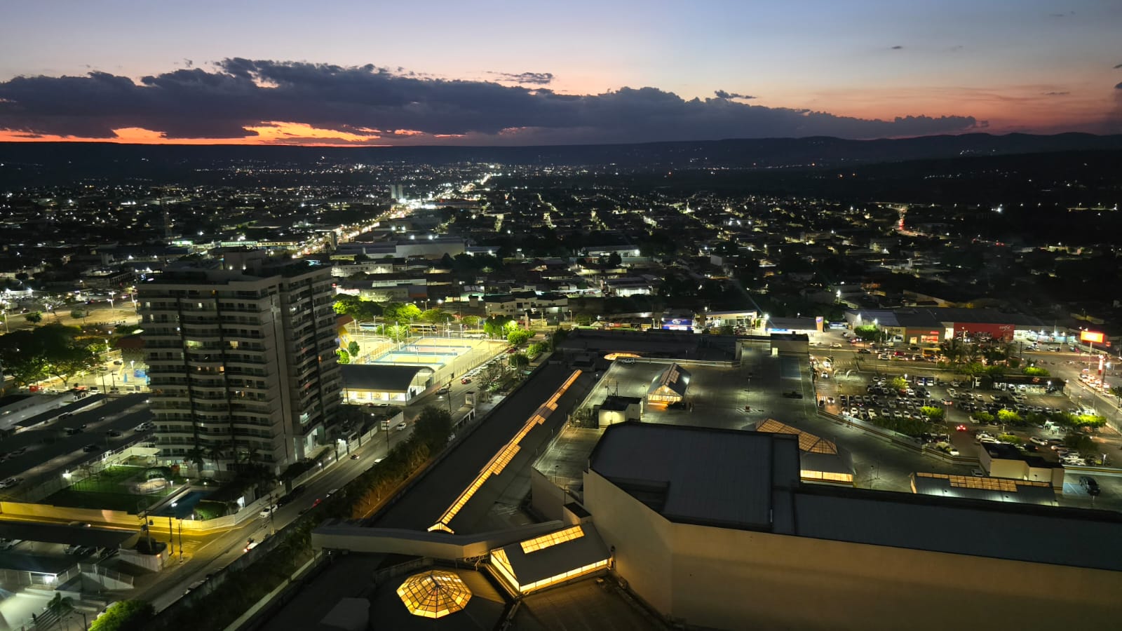 Vista noturna do Cariri a partir do 20º andar, com o céu alaranjado do pôr do sol