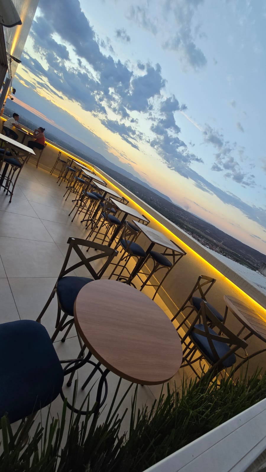 Terraço do Gran Vista ao entardecer, com mesas junto ao parapeito iluminado